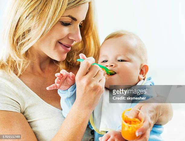 mother feeding her baby. - food in jar stock pictures, royalty-free photos & images