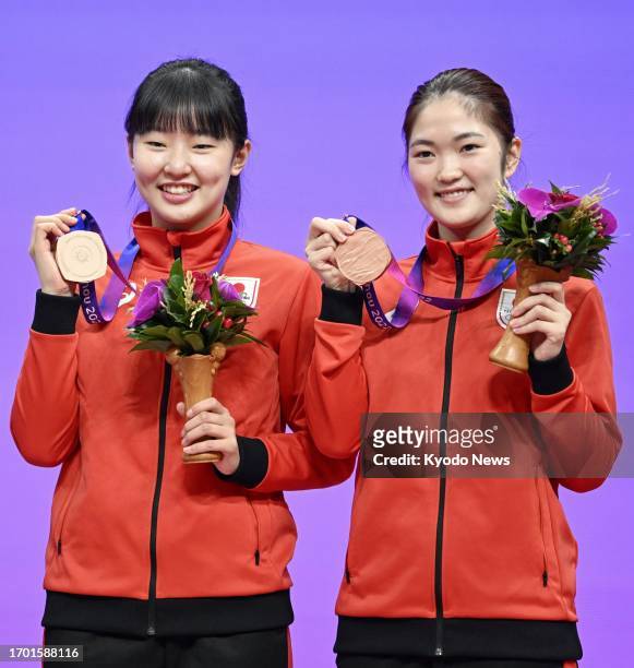 Japan's Miwa Harimoto and Miyuu Kihara pose for a photo with their bronze medals in women's doubles table tennis at the Asian Games in Hangzhou,...