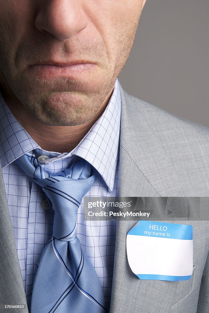Unhappy Businessman Frowns with Name Tag