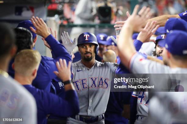 Marcus Semien of the Texas Rangers celebrates with teammates in the dugout after hitting a home run in the seventh inning against the Los Angeles...