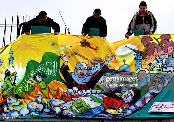 Palestinian youths hang mural of the description of Al-Shaheed or the Martyr, in support of the Intifada Martyrs, over the Tal El-hawa mosque near...