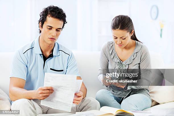 young serious couple doing their taxes. - couple counting money stock pictures, royalty-free photos & images