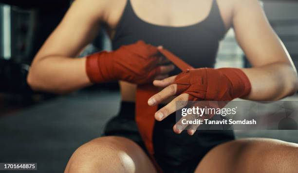 woman fighter wraps her hands with red boxing bandages, kickboxing training day in a gym. - boksring stockfoto's en -beelden