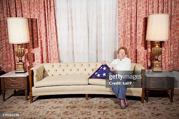 senior woman at home holding folded american flag - side table stock pictures, royalty-free photos & images