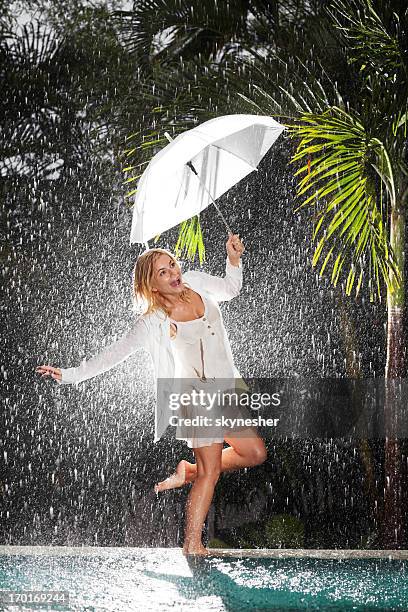 frau walking on edge of swimming pool in tropischer regen - enjoy monsoon stock-fotos und bilder