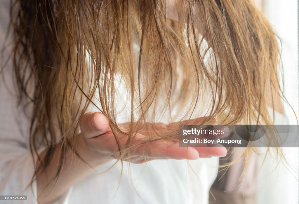 Cropped shot view of woman hand with her damaged split ended hair.