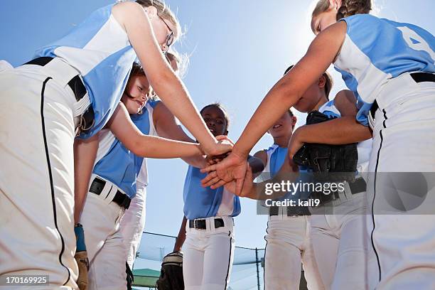 softball players with coach in huddle doing team cheer - softball sport bildbanksfoton och bilder