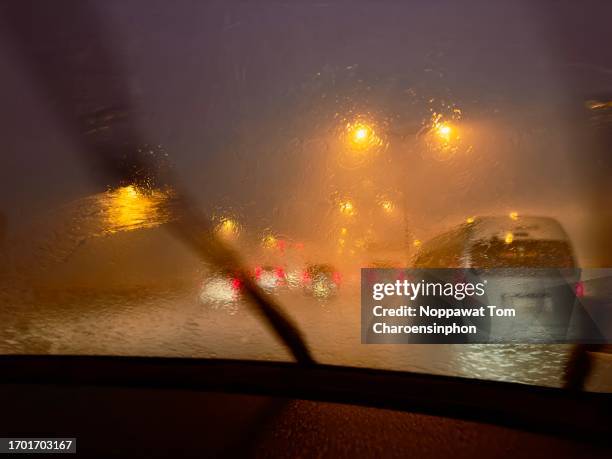 view from inside a moving car on the highway in bangkok, thailand, with raindrops on the windshield and the glow of taillights - rainwater basin stock pictures, royalty-free photos & images
