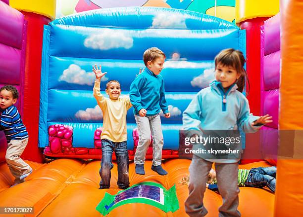 niños disfrutando del castillo inflable para saltar. - bouncing fotografías e imágenes de stock