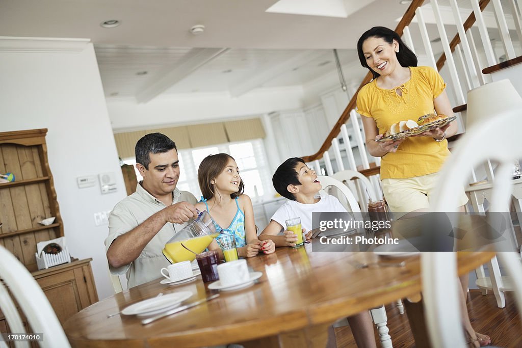 Mother Serving Breakfast With Family Sitting At Table