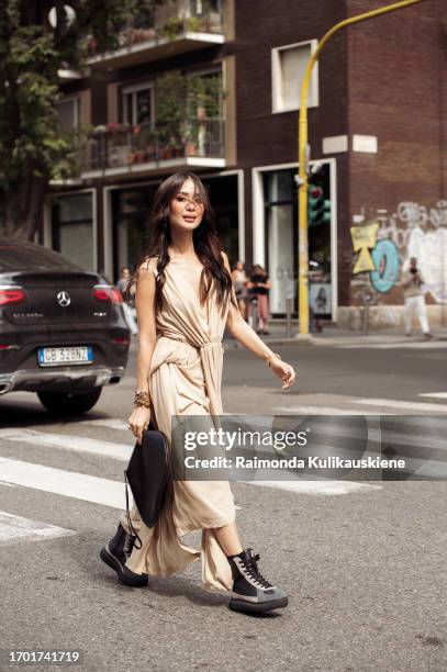 Heart Evangelista wears a beige v-neck long dress, a golden bracelet, a heart shaped Alaia black leather bag, ankle boots outside Onitsuka Tiger...