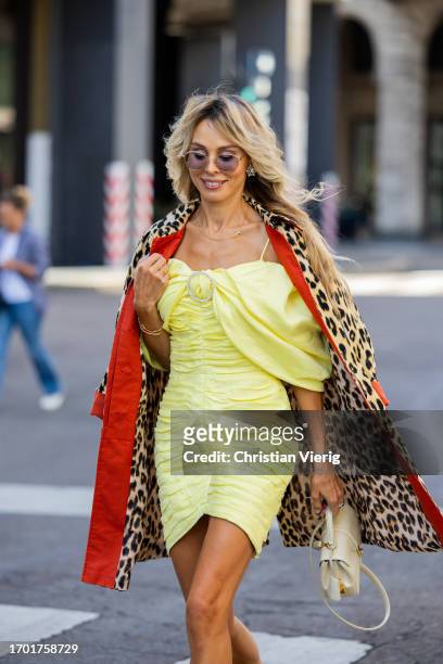 Ekaterina Mamaeva wears yellow dress Rasario, leopard print trench coat Max & Co, white bag Celine, earrings Chanel during the Milan Fashion Week -...
