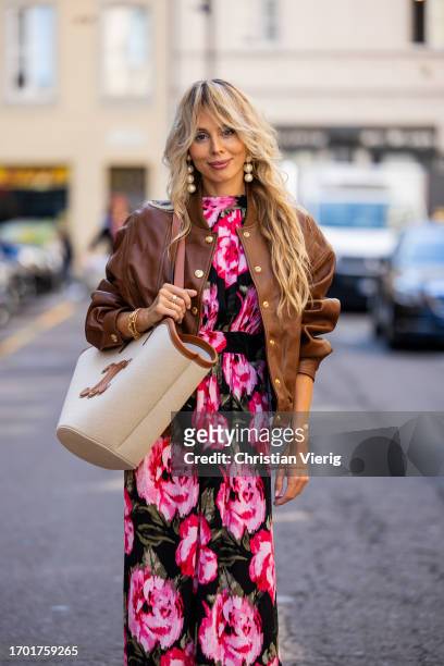 Ekaterina Mamaeva wears dress with floral print Rotate, brown college leather jacket Celine, creme white brown bag Celine, earrings Cult Gaia during...