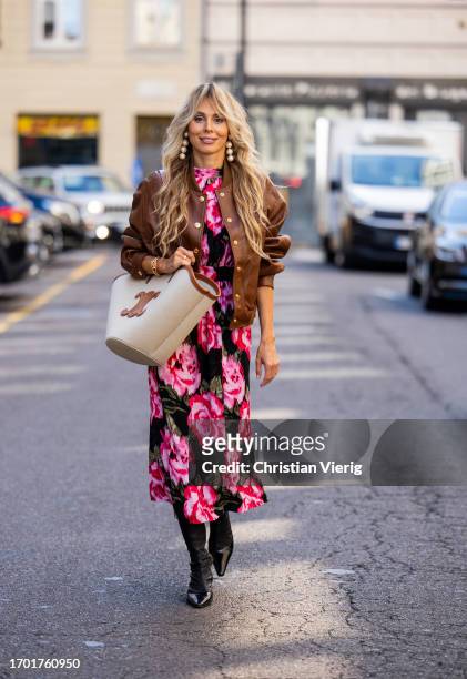 Ekaterina Mamaeva wears dress with floral print Rotate, brown college leather jacket Celine, black boots Acne Studios, creme white brown bag Celine,...