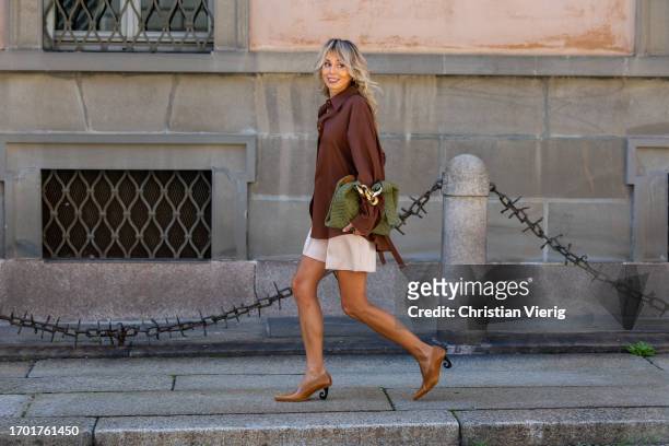 Ekaterina Mamaeva wears brown button shirt Le17Septembre, creme white shorts Chloe, brown pointed heels shoes Kalda, green bag JW Anderson, necklace...