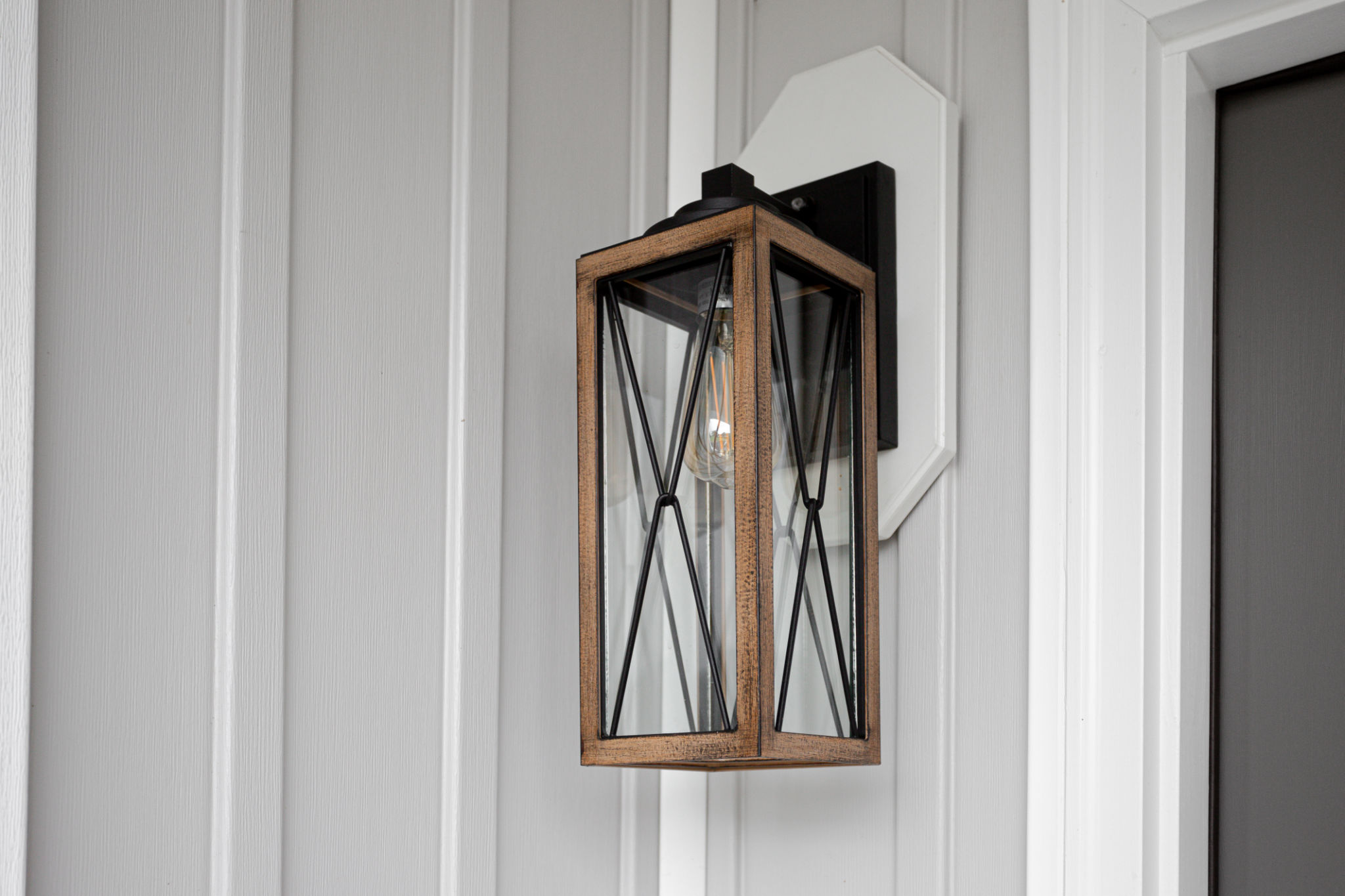 Southern Rustic Farmhouse Front Porch Light Sconce Next To Front Door and Grey Siding. Copyspace Southern Rustic Farmhouse Front Porch Light Sconce Next To Front Door and Grey Siding. Copyspace