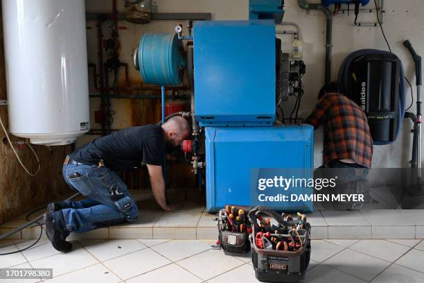 Workers remove an oil boiler before installing a heat pump in a private home in Saint-Didier, western France on October 2, 2023. The heat pump,...