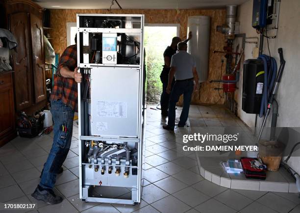 Workers install a heat pump in a private home in Saint-Didier, western France on October 2, 2023. The heat pump, praised by French President, is...