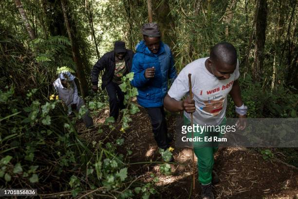 Porters and mountain guide David Wangari walk near the Percival Waterfall near Mount Kenya on September 29, 2023 in Mount Kenya National Park, Kenya....