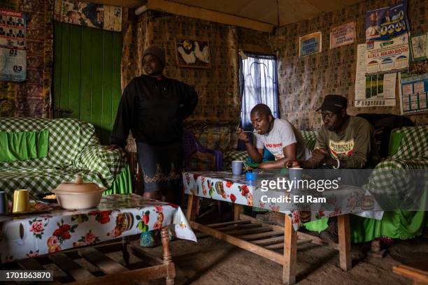Porter Johana Macharia's family members serve a meal to his porter friends at his home in Gitinga Village, where 60% of the men work as mountain...