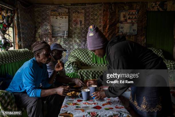 Porter Johana Macharia's family members serve a meal to his porter friends at his home in Gitinga Village, where 60% of the men work as mountain...