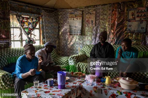 Porter Johana Macharia's and family members eat a meal with his porter friends at his home in Gitinga Village, where 60% of the men work as mountain...
