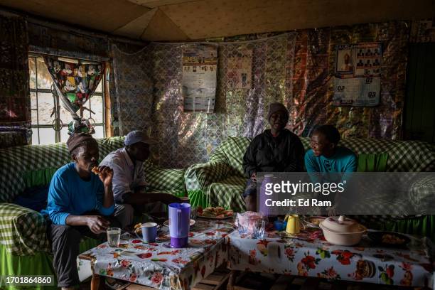 Porter Johana Macharia's and family members eat a meal with his porter friends at his home in Gitinga Village, where 60% of the men work as mountain...