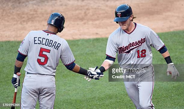 Minnesota Twins shortstop Eduardo Escobar slaps hands with catcher Chris Herrmann after Herrmann scored the game-willing run on a hit by catcher Ryan...