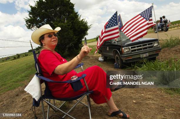 Diane Wallin, a supporter of US President George W. Bush, holds up her finger stained with green ink at passing motorists near the makeshift camp of...