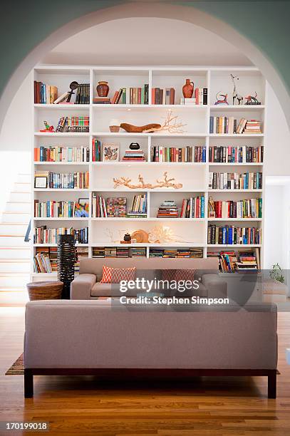light-filled living room with tall bookshelves - bookcase stockfoto's en -beelden