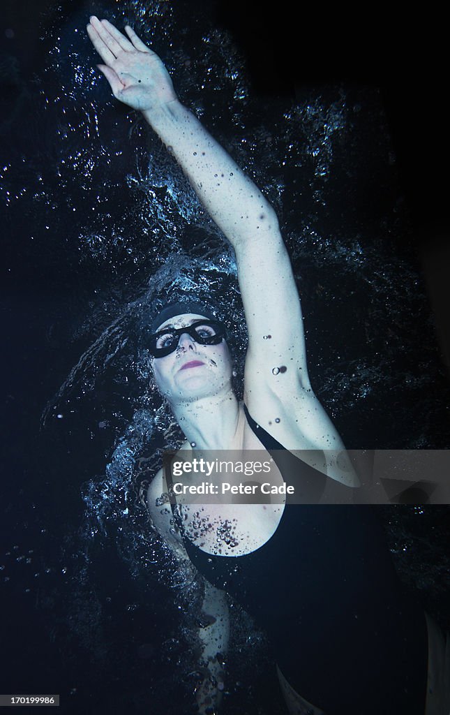 Woman swimming at night in pool