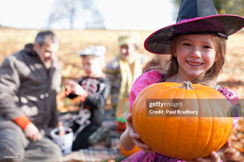 Mädchen in Halloween-Kostümen hält Kürbis