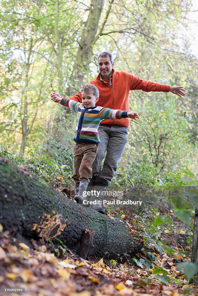 Father helping son cross log outdoors