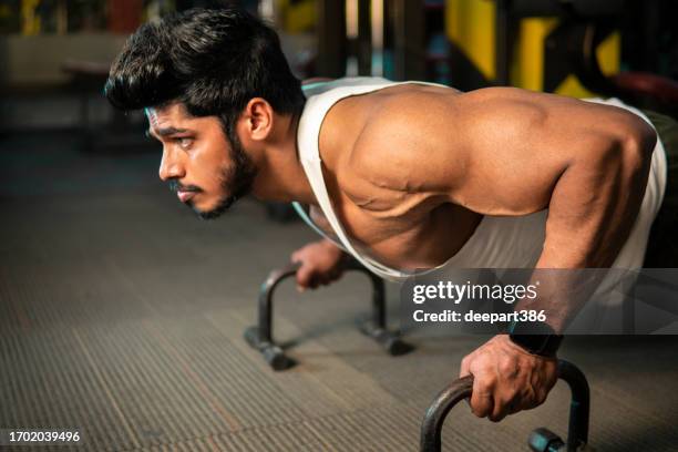 joven fuerte y musculoso haciendo ejercicio de barras de flexión en el gimnasio. - handsome bodybuilders fotografías e imágenes de stock