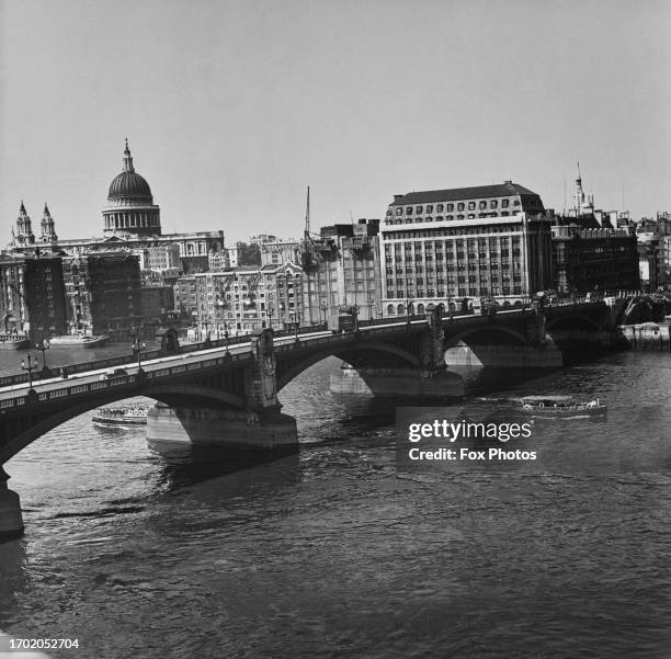 Boats on the River Thames passing underneath Southwark Bridge, London, circa 1955.