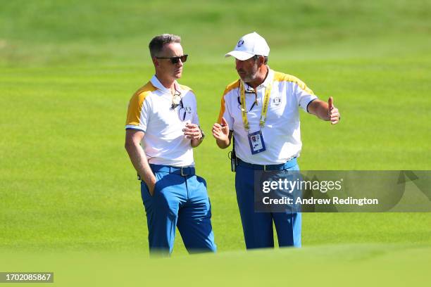 Luke Donald, Captain of Team Europe talks with Jose Maria Olazabal, Vice Captain of Team Europe on the seventh green during a practice round prior to...