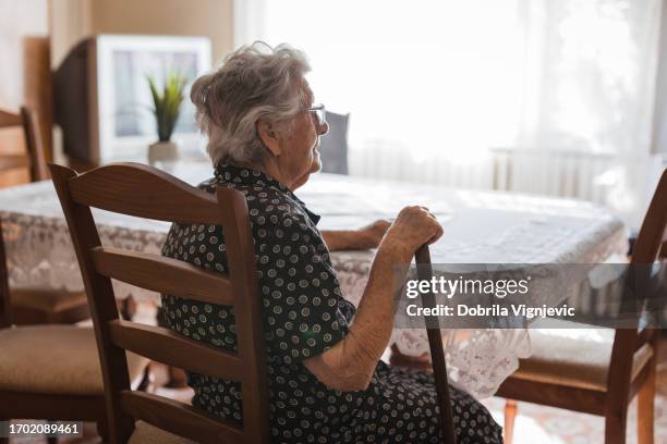 senior lady reflecting at dining table - ziekte van alzheimer stockfoto's en -beelden