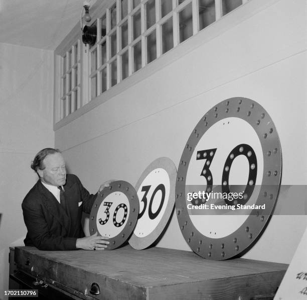 Man showing new road signs indicating 30 mile an hour speed limits, introduced by the Ministry of Transport, February 12th 1957.