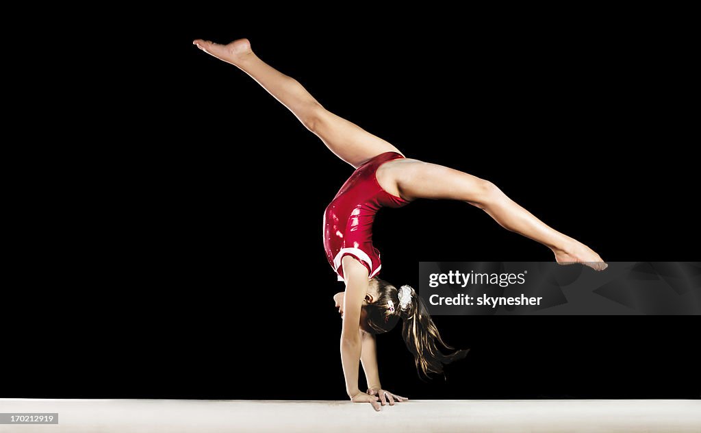 Young gymnast girl exercising on balance beam.