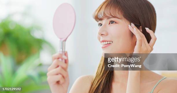 若いアジアの女性は鏡を見て - 若い女性 日本人 顔 ストックフォトと画像