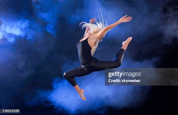 professional ballerina jumping through the fog. - ballet black and white stock pictures, royalty-free photos & images