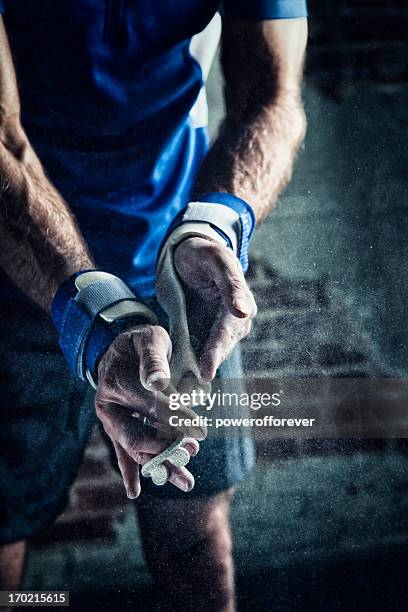 gymnast dusting chalk on his hands - gymnast stock pictures, royalty-free photos & images