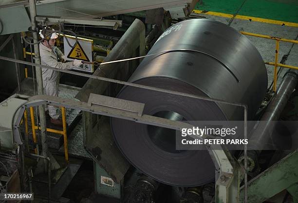 This photo taken on June 6, 2013 shows a worker loading a roll of steel at the hot rolling plant at the Baosteel steel mill in Shanghai during a tour...