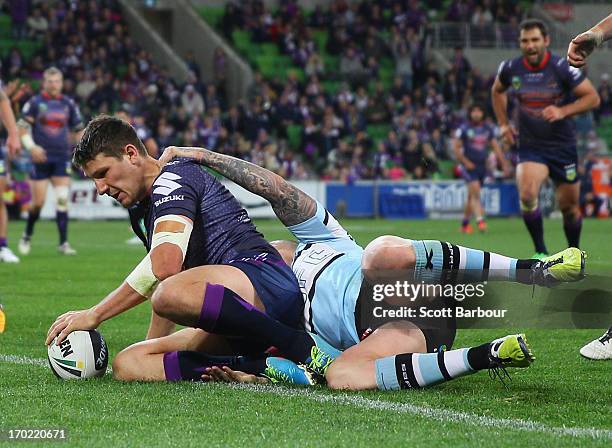 Gareth Widdop of the Storm scores a try despite the tackle of Todd Carney of the Sharks during the round 13 NRL match between the Melbourne Storm and...