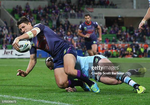 Gareth Widdop of the Storm scores a try despite the tackle of Todd Carney of the Sharks during the round 13 NRL match between the Melbourne Storm and...