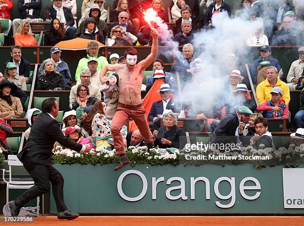 Protester runs onto court with a lit flare before the start of a game in the Men's Singles final match between Rafael Nadal of Spain and David Ferrer...