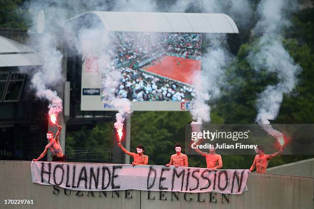 Protesters light flares and unfurl a banner on the top of Court Suzanne Lenglen as Rafael Nadal of Spain and David Ferrer of Spain compete on Court...