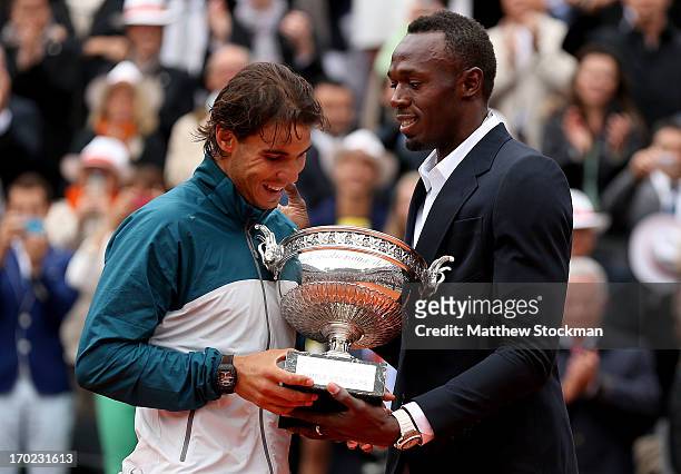 Rafael Nadal of Spain is presented with the Coupe des Mousquetaires trophy by Usian Bolt after the men's singles final against David Ferrer of Spain...
