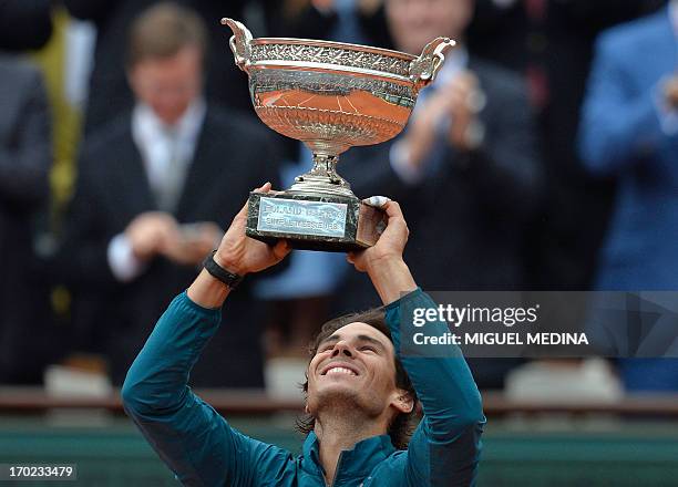 Spain's Rafael Nadal holds up the Musketeers trophy after winning the 2013 French tennis Open final against Spain's David Ferrer at the Roland Garros...