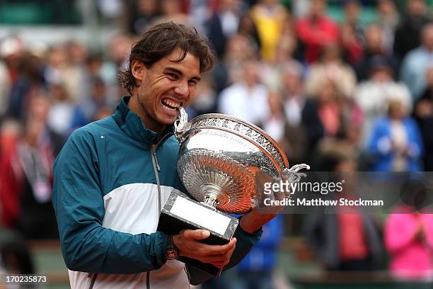 Rafael Nadal of Spain bites the Coupe des Mousquetaires trophy as he celebrates after the men's singles final against David Ferrer of Spain during...